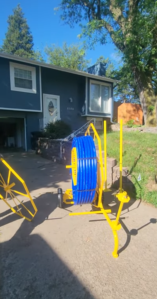 Yellow hose reel with blue hose outside a house on a sunny day